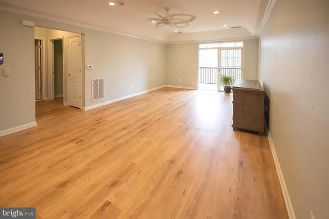 a view of empty room with wooden floor and fan