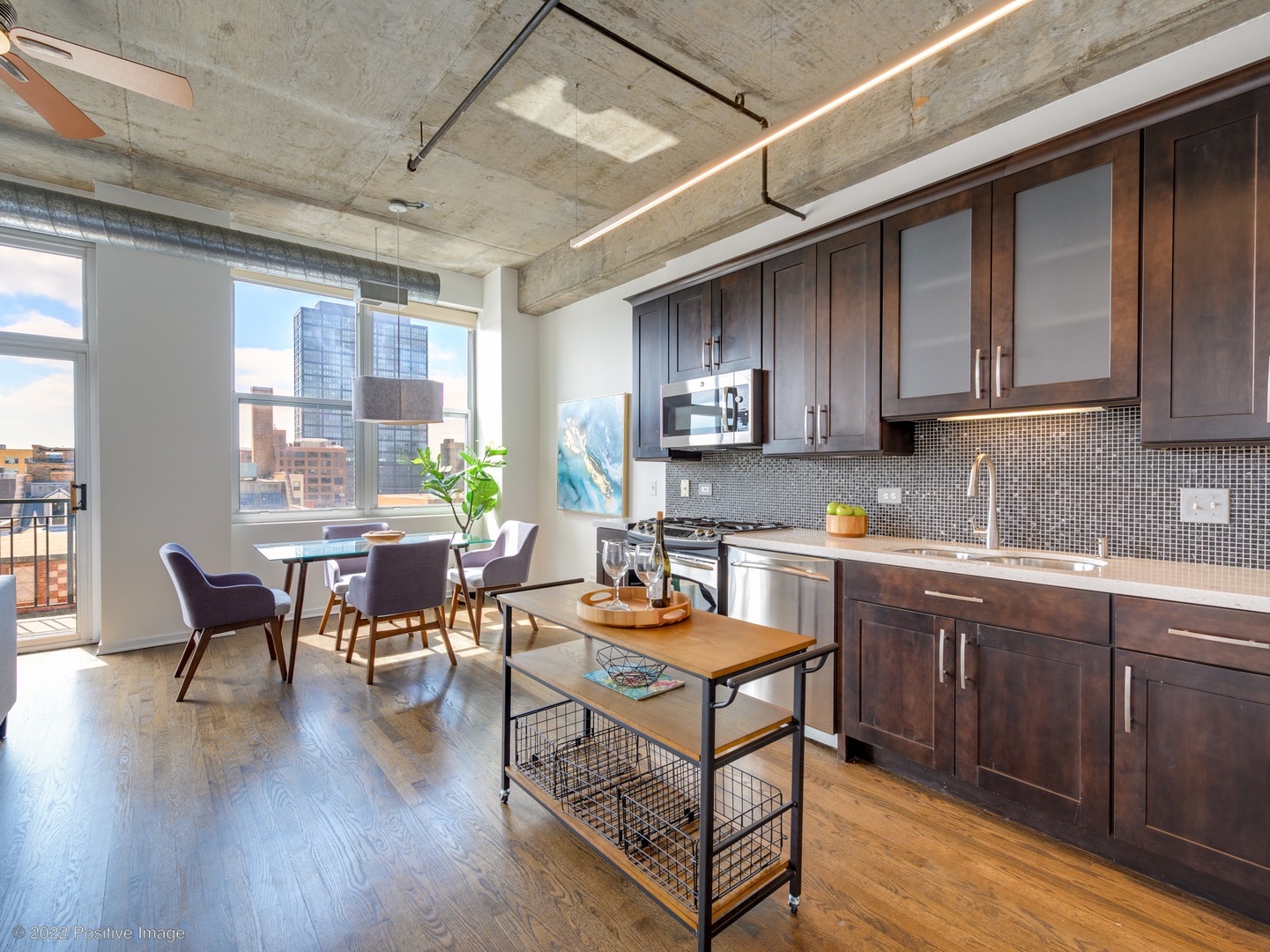 1000 West Adams Street, Unit 613 Chicago, IL 60607 - Photo 5 of 26 a open kitchen with stainless steel appliances granite countertop a stove top oven a sink dishwasher a dining table and chairs with wooden floor