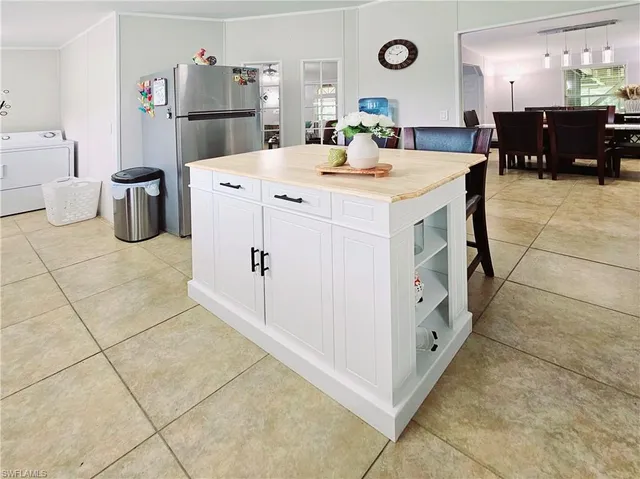 a large white kitchen with a stove a refrigerator and a dining table