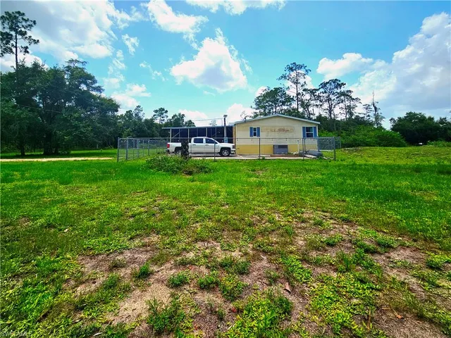 a view of a house with a big yard and large trees