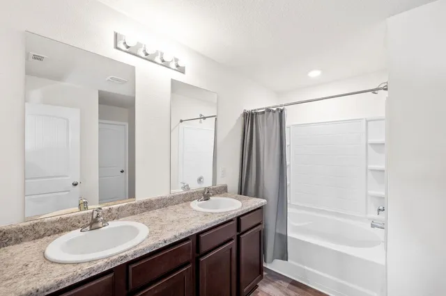 a bathroom with a granite countertop sink mirror and a bathtub