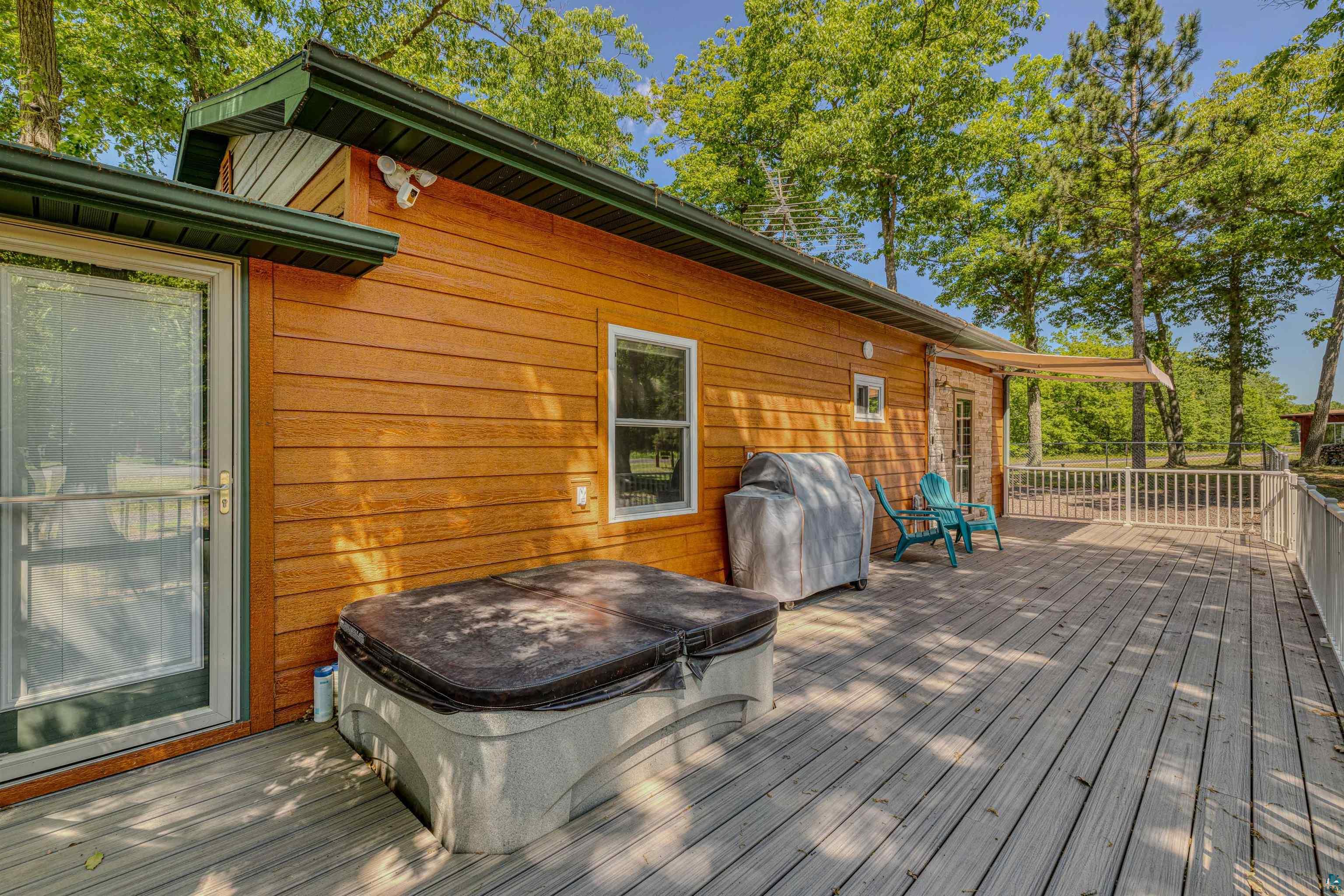 66075 Rooster Road Iron River, WI 54847 - Photo 32 of 52 Expansive exterior deck featuring a hot tub, wood siding, multiple windows, and a sliding glass door