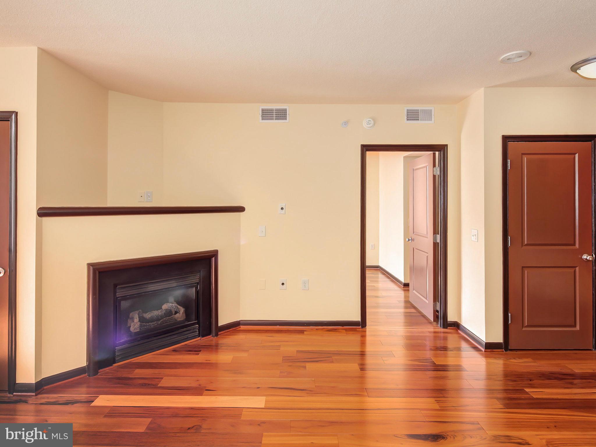 851 North Glebe Road, Unit 921 Arlington, VA 22203 - Photo 6 of 29 an empty room with wooden floor fireplace and windows