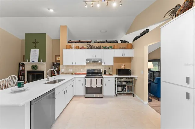 a living room with stainless steel appliances furniture a rug and a kitchen view