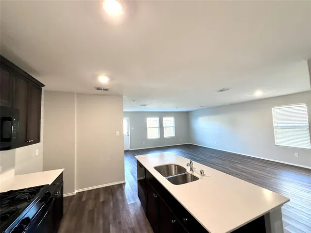 a kitchen with a sink a stove and wooden floor