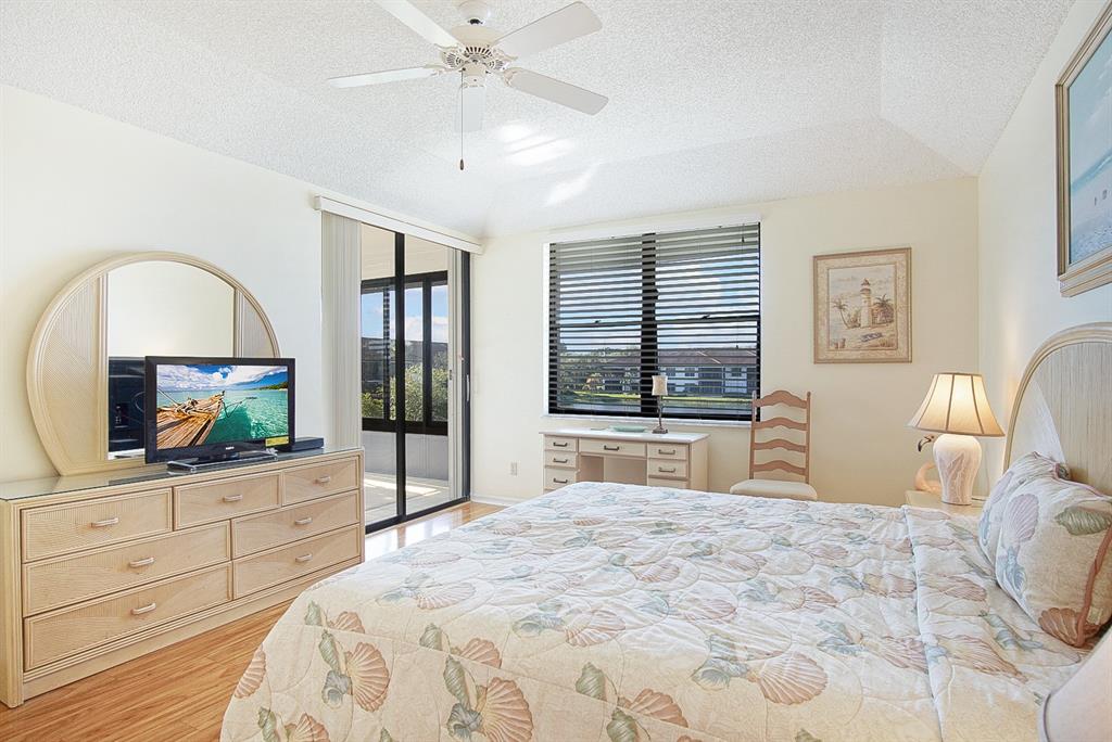 6081 Southeast Landing Way, Unit 9 Stuart, FL 34997 - Photo 12 of 31 a bedroom with a bed a mirror on dresser and a flat screen tv