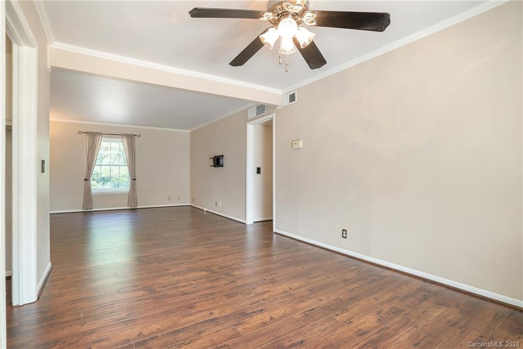 2628 Park Road, Unit H Charlotte, NC 28209 - Photo 5 of 39 an empty room with wooden floor chandelier fan and windows