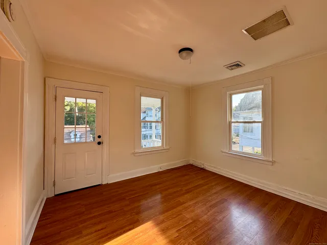 a view of an empty room with wooden floor and a window