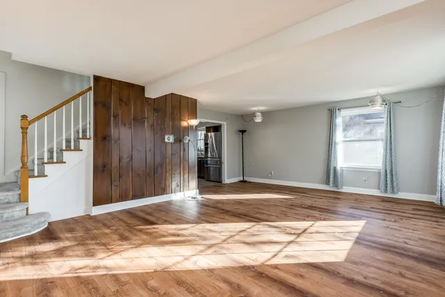 a view of a livingroom with wooden floor and stairs
