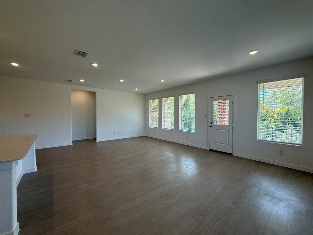 3025 Timber Rdg Drive Anna, TX 75409 - Photo 9 of 23 Open-concept living space with wood-finish flooring, recessed lighting, multiple windows with blinds, and a white paneled door with an integrated window