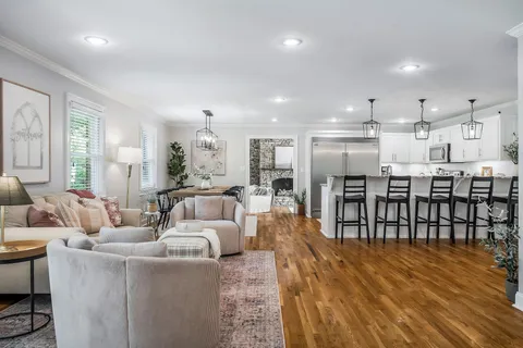 a living room with furniture a wooden floor and kitchen view