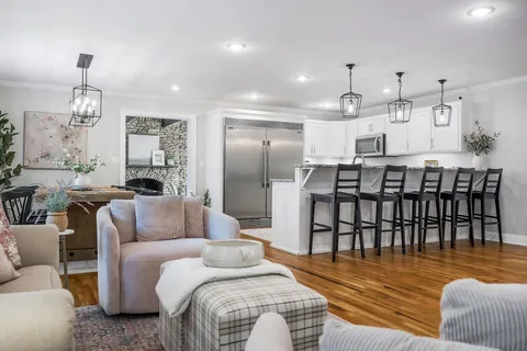 a kitchen with stainless steel appliances a dining table chairs and cabinets