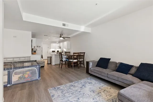 a living room with furniture and a dining table with wooden floor