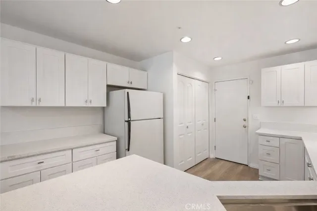 a kitchen with white cabinets and refrigerator