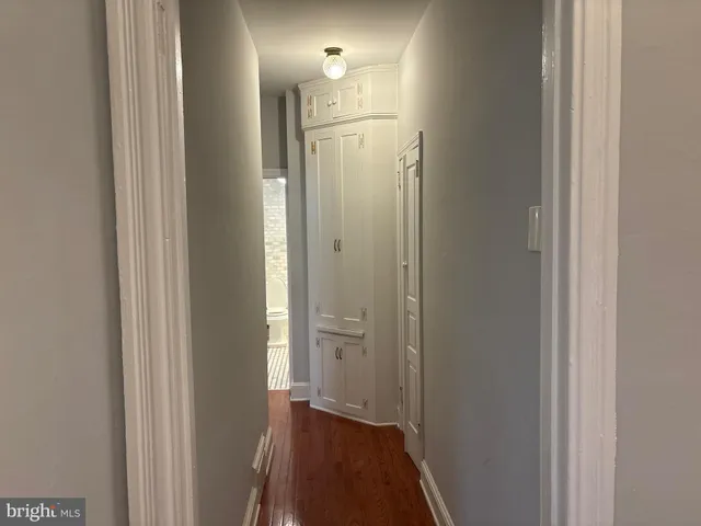 a view of a hallway with wooden floor and a bathroom