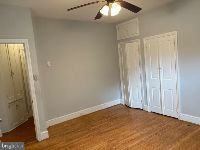 an empty room with wooden floor and hallway