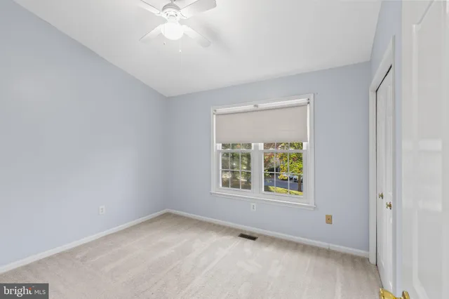 an empty room with a window and a fan