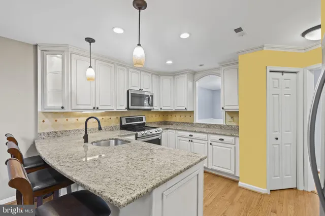 a kitchen with stainless steel appliances granite countertop a sink a stove a refrigerator cabinets and wooden floor