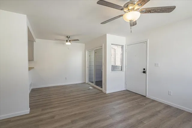 an empty room with wooden floor fan and windows