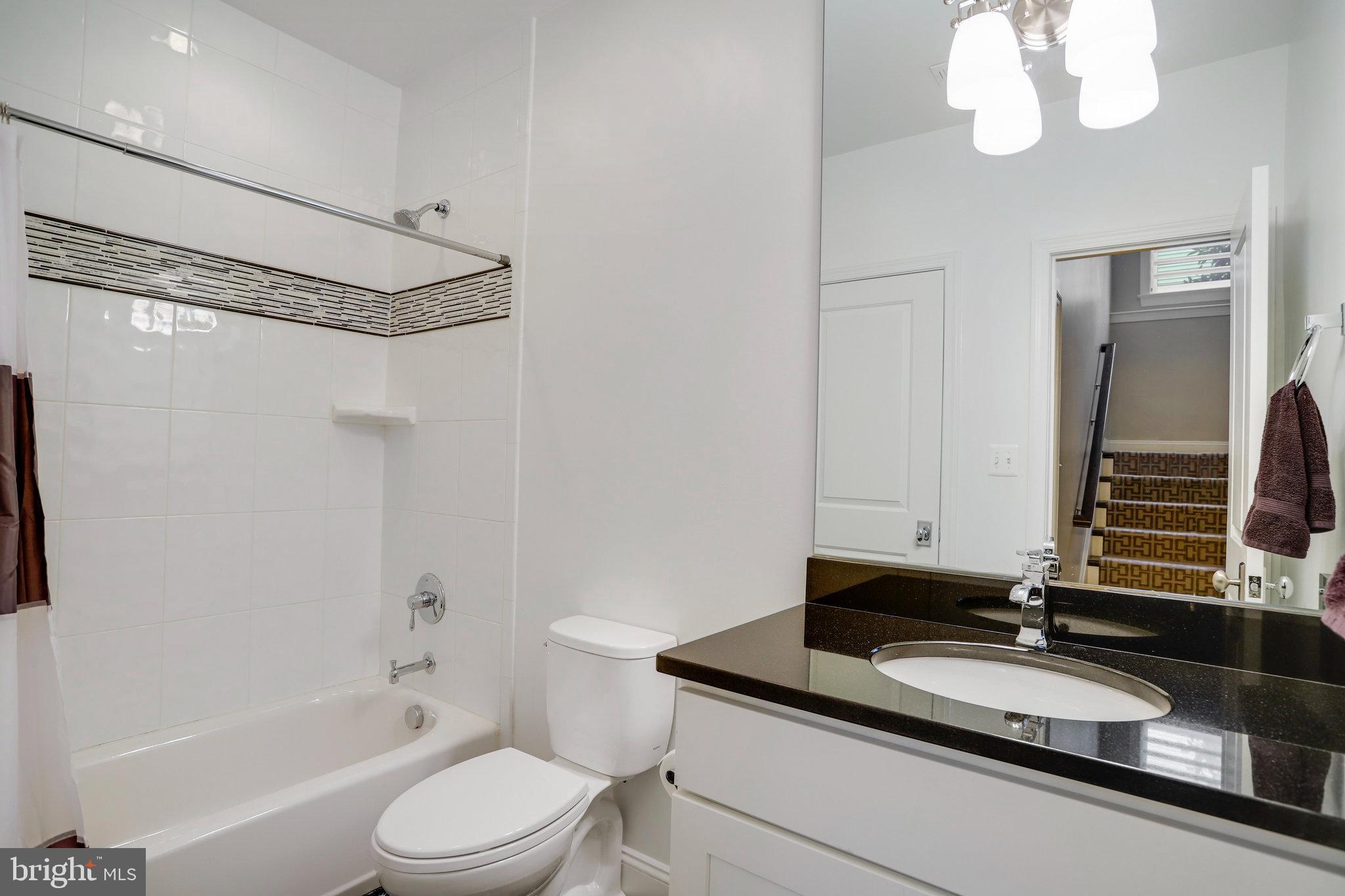 4548 Windsor Lane Bethesda, MD 20814 - Photo 28 of 39 a bathroom with a granite countertop sink a toilet and a mirror