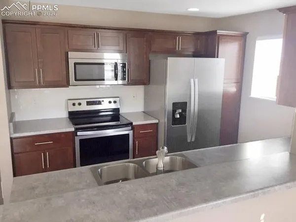 a kitchen with granite countertop a refrigerator and a stove top oven