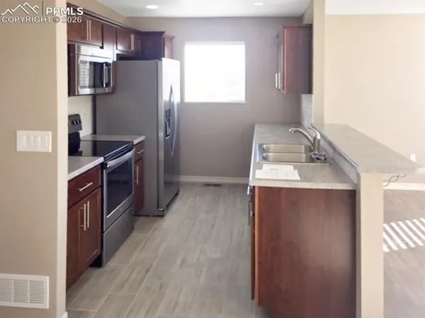 a kitchen with stainless steel appliances granite countertop a refrigerator a stove a sink and dishwasher