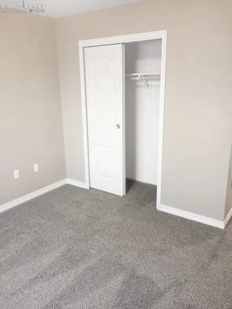 a view of an empty room with closet and a hallway