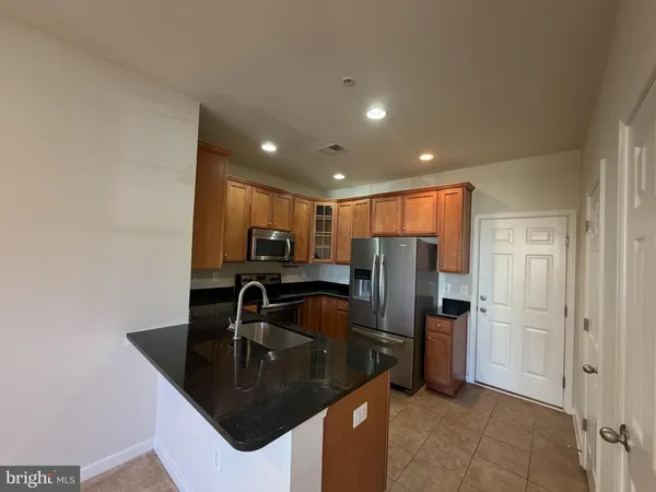 a kitchen with stainless steel appliances granite countertop a sink a refrigerator and a granite counter tops