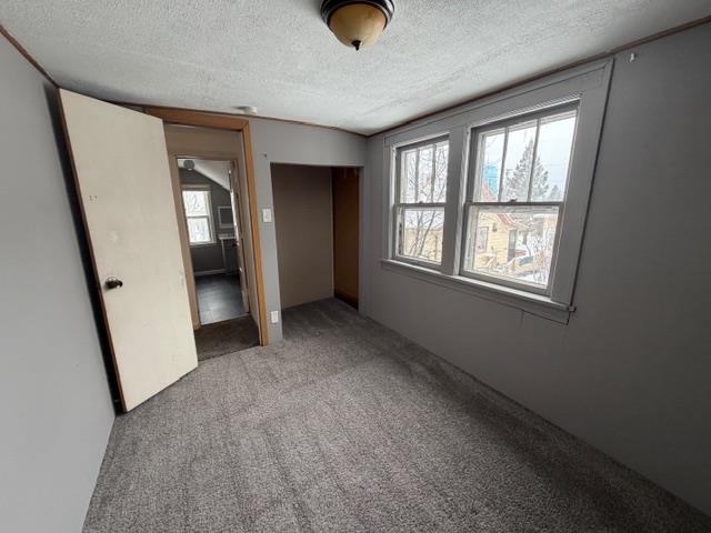 824 12th Street North Virginia, MN 55792 - Photo 18 of 34 Unfurnished bedroom featuring a closet, carpet floors, and a textured ceiling