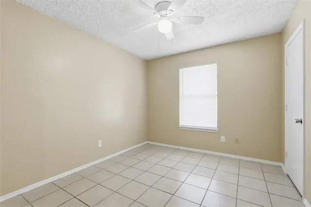 an empty room with a chandelier fan and windows