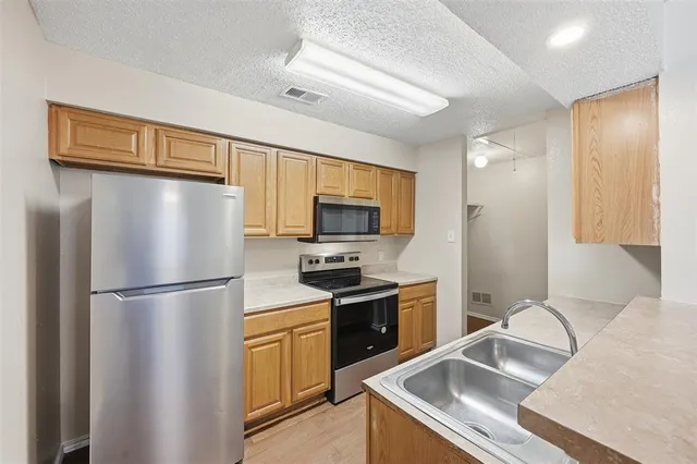 a kitchen with stainless steel appliances granite countertop a refrigerator a stove a sink and a microwave
