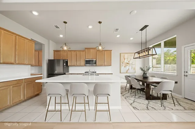 a kitchen with stainless steel appliances kitchen island granite countertop a sink and a refrigerator