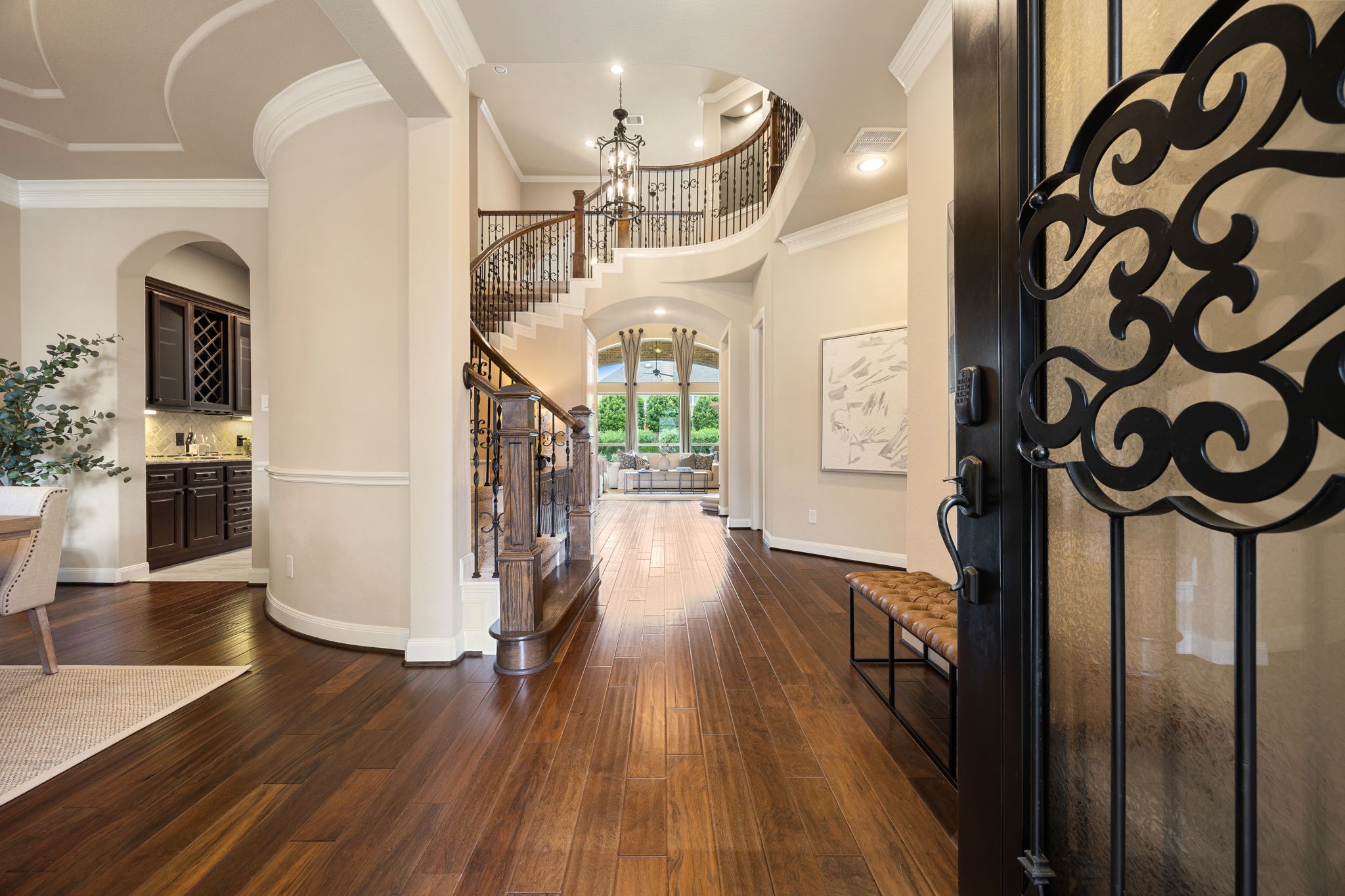 3306 Reston Landing Lane Katy, TX 77494 - Photo 4 of 50 Step inside to rich hardwood flooring, soaring ceilings, and walls of windows that flood the home with natural light, highlighted by a sweeping curved staircase with elegant wrought-iron spindles.