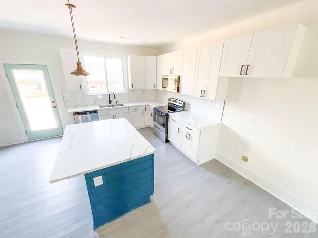 a large white kitchen with sink and refrigerator