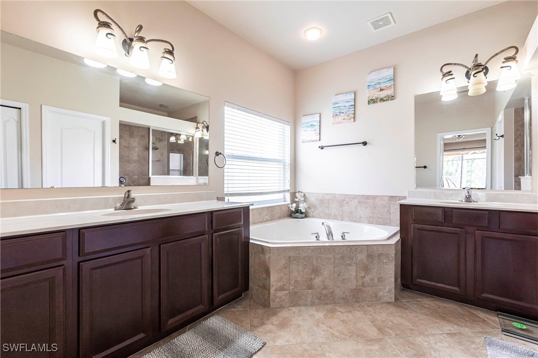2808 Via Piazza Loop Fort Myers, FL 33905 - Photo 17 of 49 a spacious bathroom with a bathtub double sink and mirror