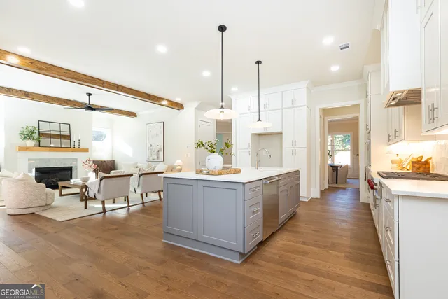 a large white kitchen with living room and stainless steel appliances