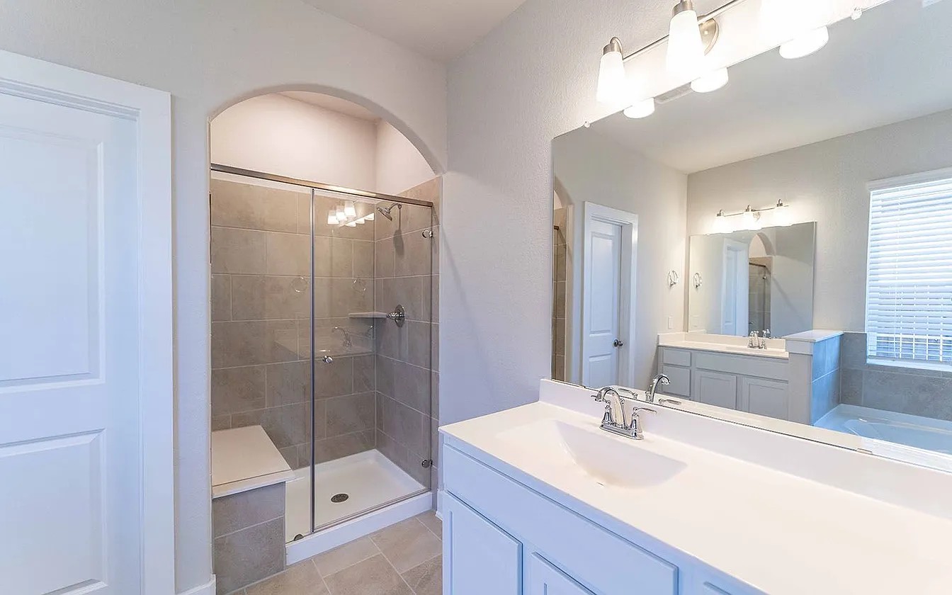 450 Durian Loop Buda, TX 78610 - Photo 13 of 17 A well-appointed primary bathroom showcases a spacious tiled shower and a generous double vanity.