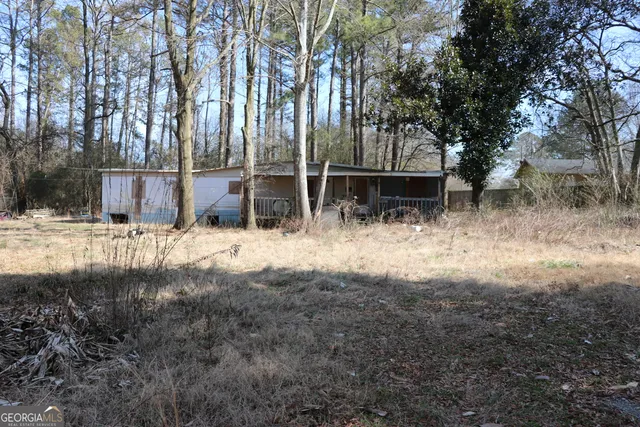 a view of backyard with large trees and wooden fence