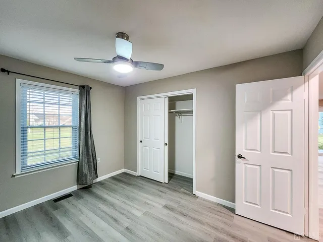 a view of empty room with wooden floor and fan