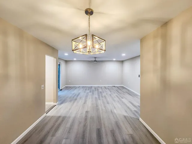 a view of empty room with wooden floor and chandelier