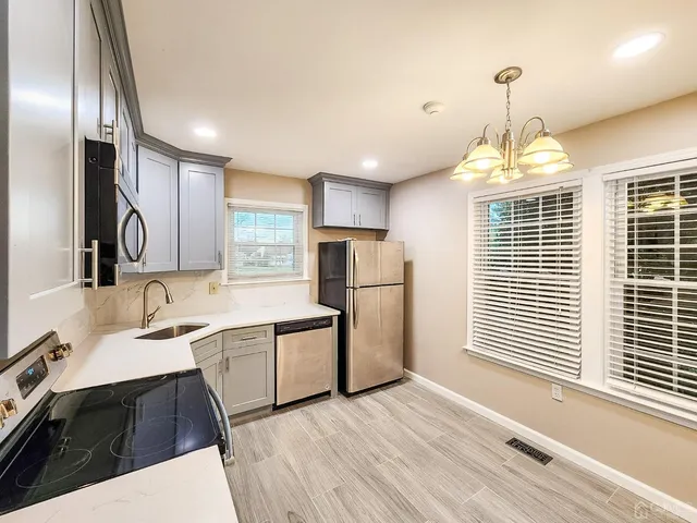 a kitchen with stainless steel appliances a sink a stove a refrigerator cabinets and a large window