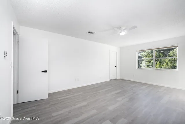 an empty room with wooden floor and windows