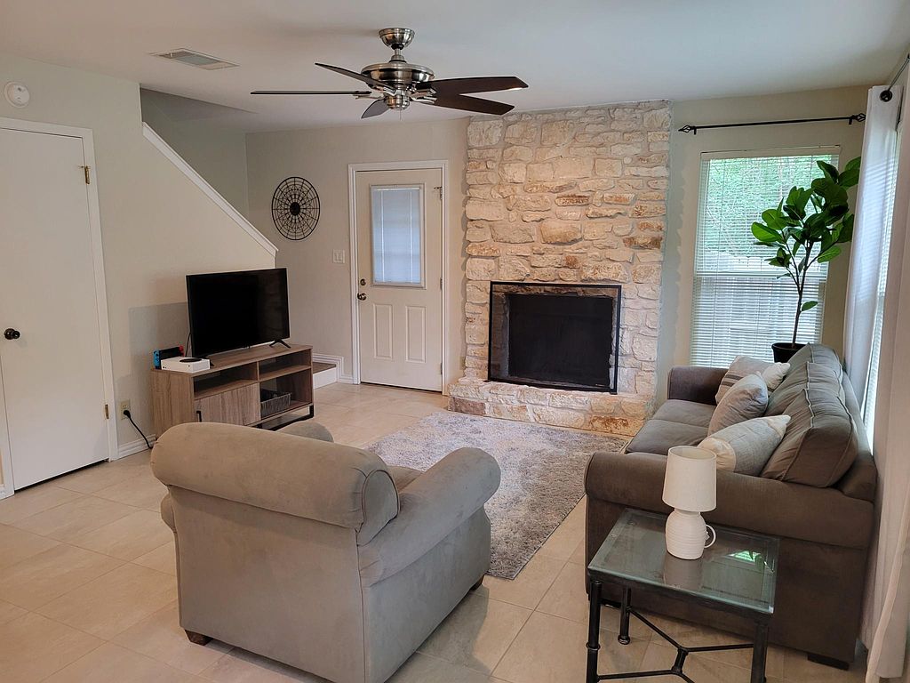 1401 Camp Craft Road, Unit C Austin, TX 78746 - Photo 1 of 12 A cozy living space features a handsome stone fireplace and sleek tile flooring.