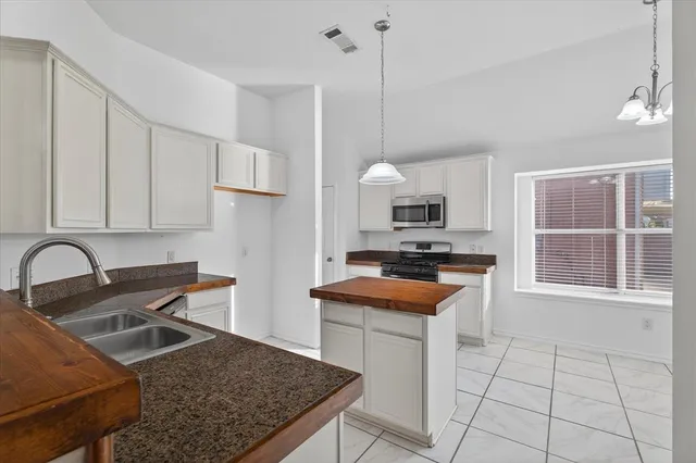 a kitchen with stainless steel appliances granite countertop a stove a sink and a microwave