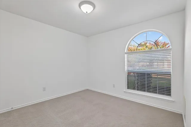 an empty room with a chandelier fan and windows