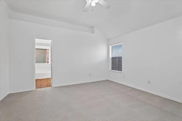 an empty room with chandelier fan and windows