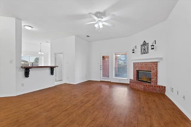 a view of an empty room with wooden floor and a fireplace