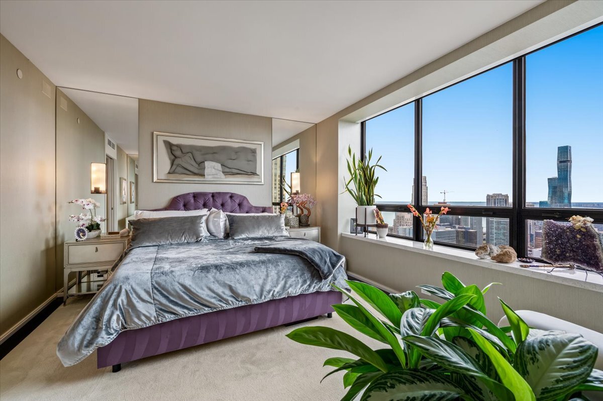 180 East Pearson Street, Unit 5107 Chicago, IL 60611 - Photo 23 of 42 a bedroom with a balcony a large bed and a potted plant