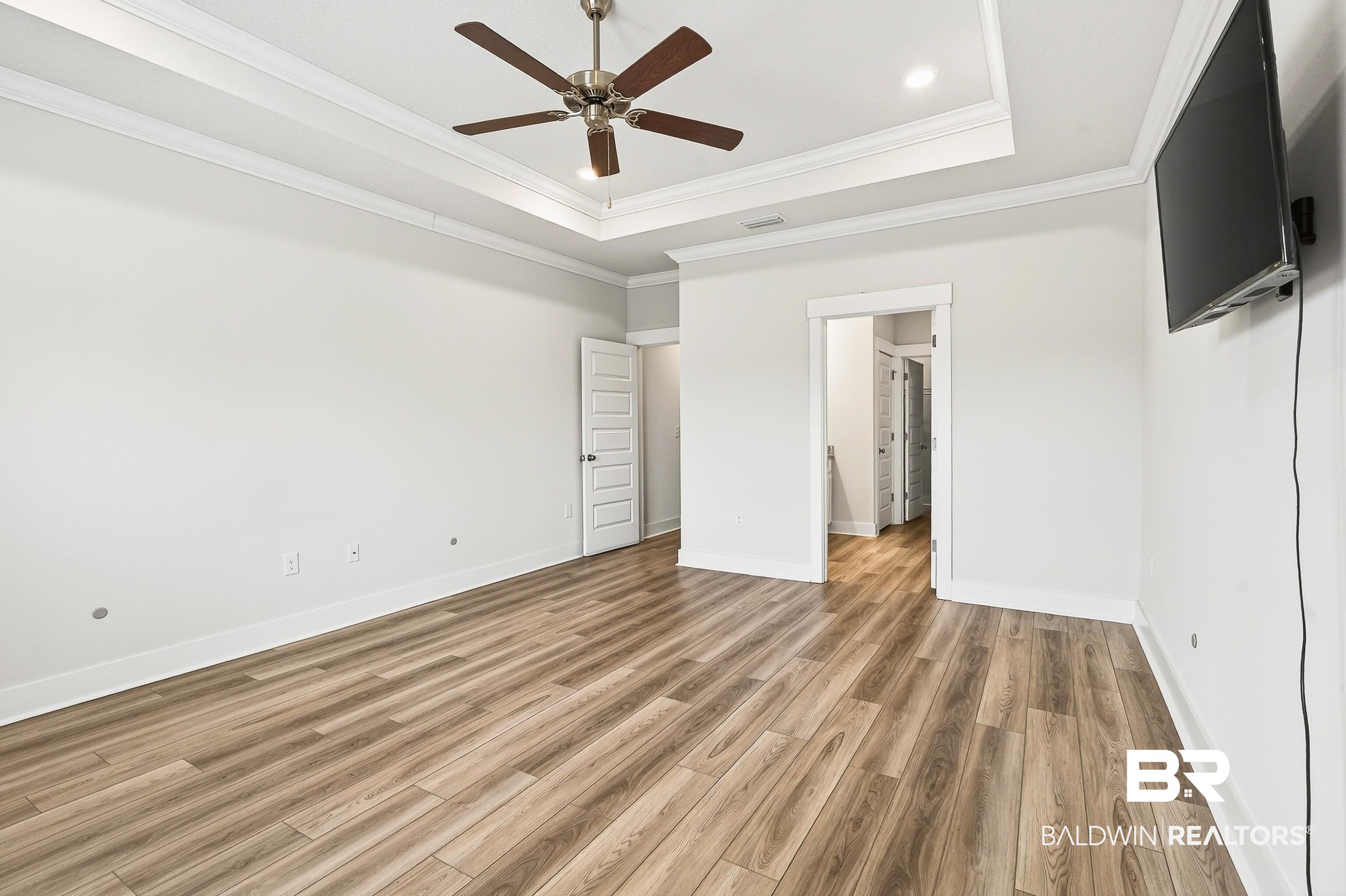 1728 Partridge Street Foley, AL 36535 - Photo 17 of 37 Unfurnished bedroom featuring light wood-style flooring, a ceiling fan, crown molding, and a raised ceiling