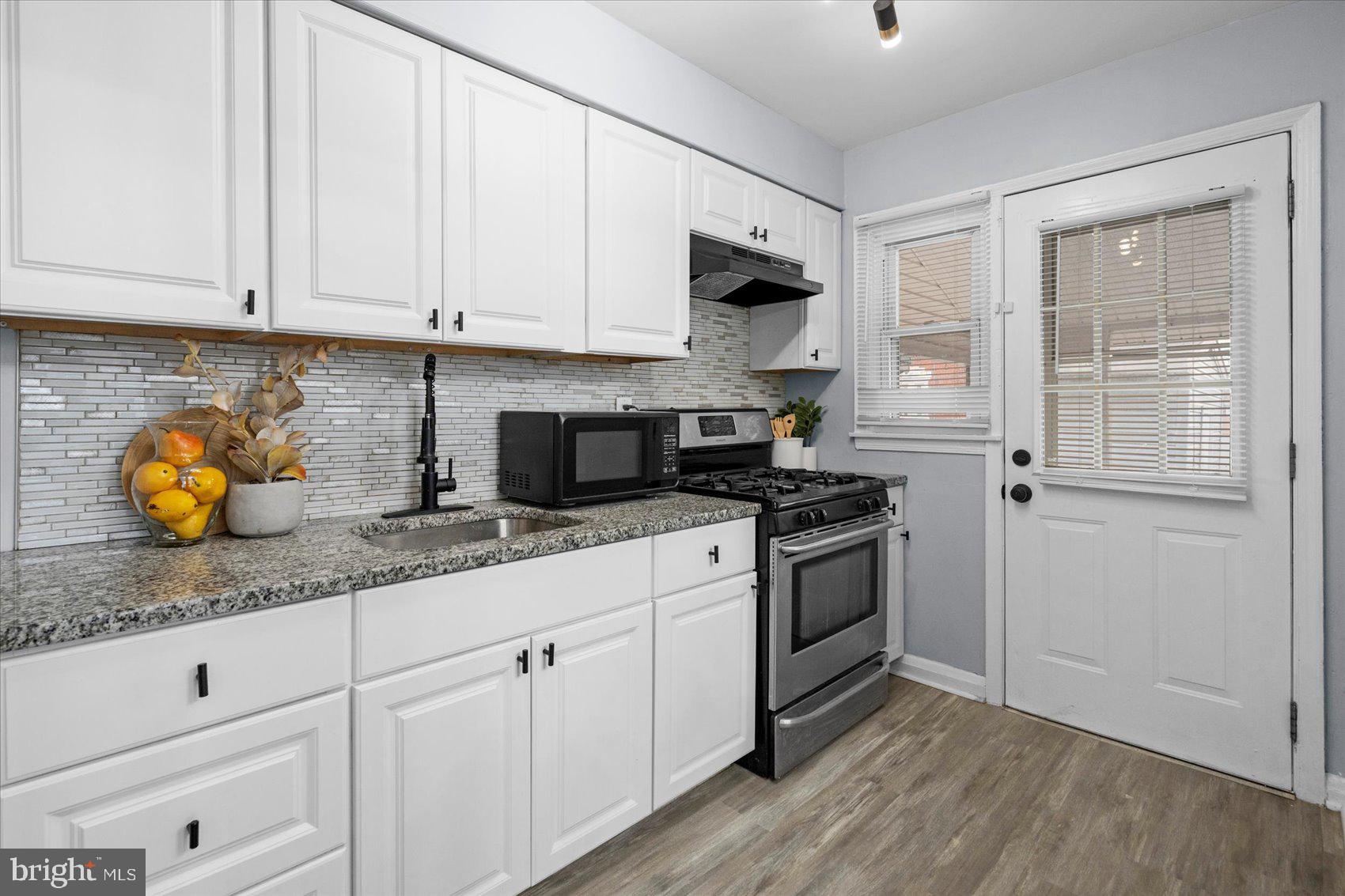 8411 Kavanagh Road Baltimore, MD 21222 - Photo 13 of 48 a kitchen with stainless steel appliances granite countertop a sink a stove and white cabinets